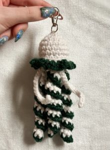 Hand holding crochet keychain shaped like a jellyfish
