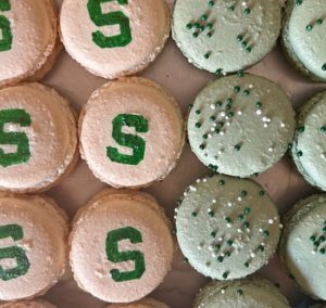 Pink macaroons with a green S and green macaroons with green and white sprinkles