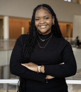 Woman wearing black standing with arms crossed and smiling