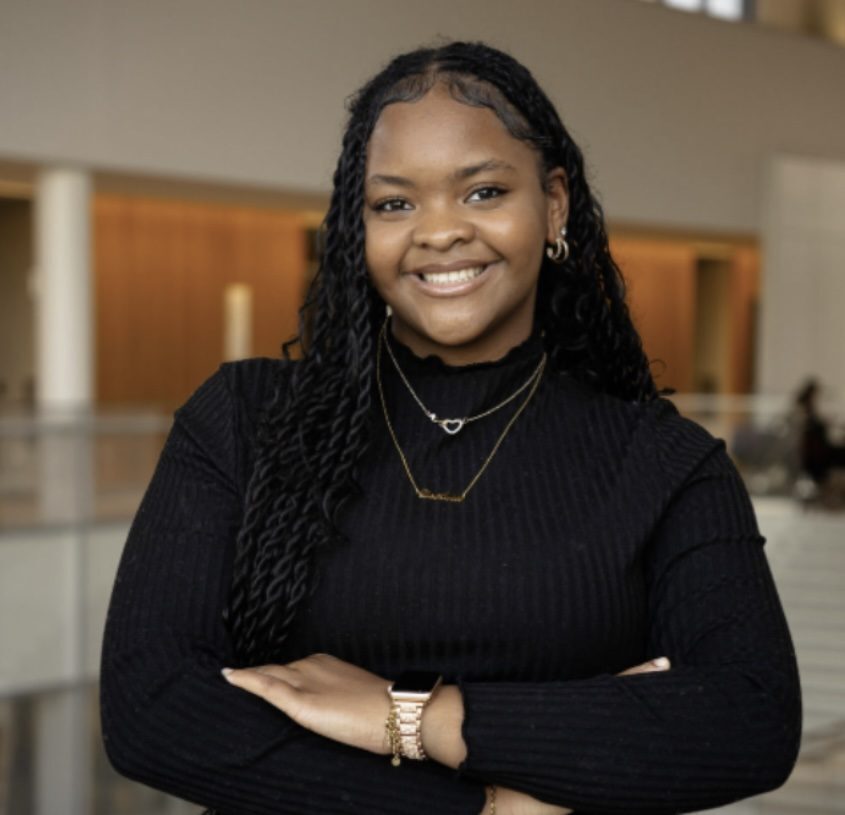 Woman wearing black standing with arms crossed and smiling