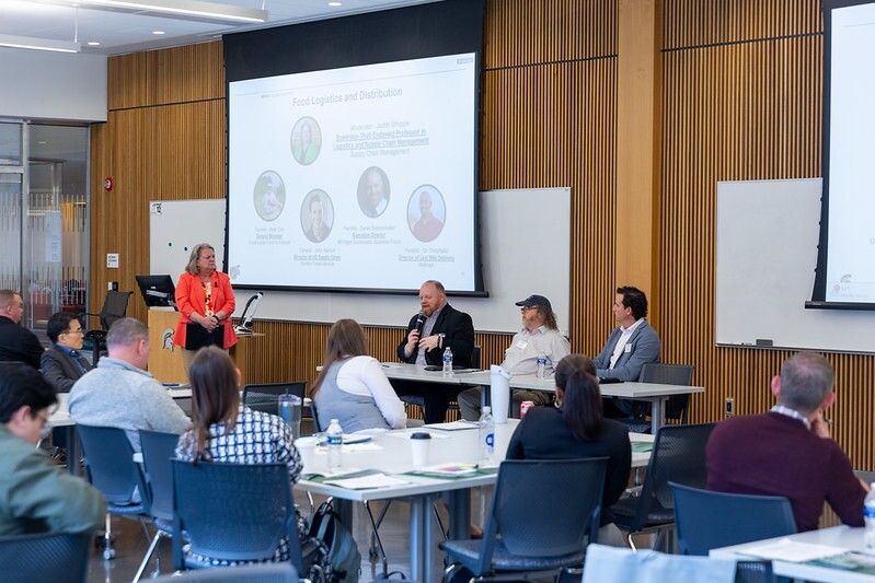 Panel speakers at the front of the room speaking to symposium attendees.