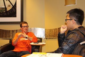PWC staff member sits with a student at Broad in training session.
