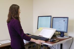 Kathy Petroni stands, working at her desk