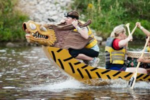 A woman stands at the helm of a dragon boat