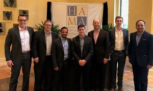 Two hospitality business students pose with faculty and professionals at the HAMA conference.