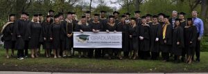 Faculty and students pose together for a picture and hold a sign which reads "Graduates MS in Management, Strategy and Leadership"