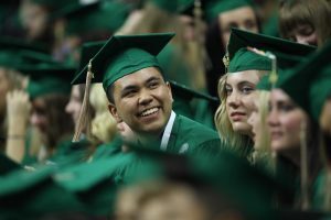A Broad College of Business graduate smiles while awaiting the start of commencement activities Saturday, May 5 at the Breslin Center. Photo by Matt Mitchell