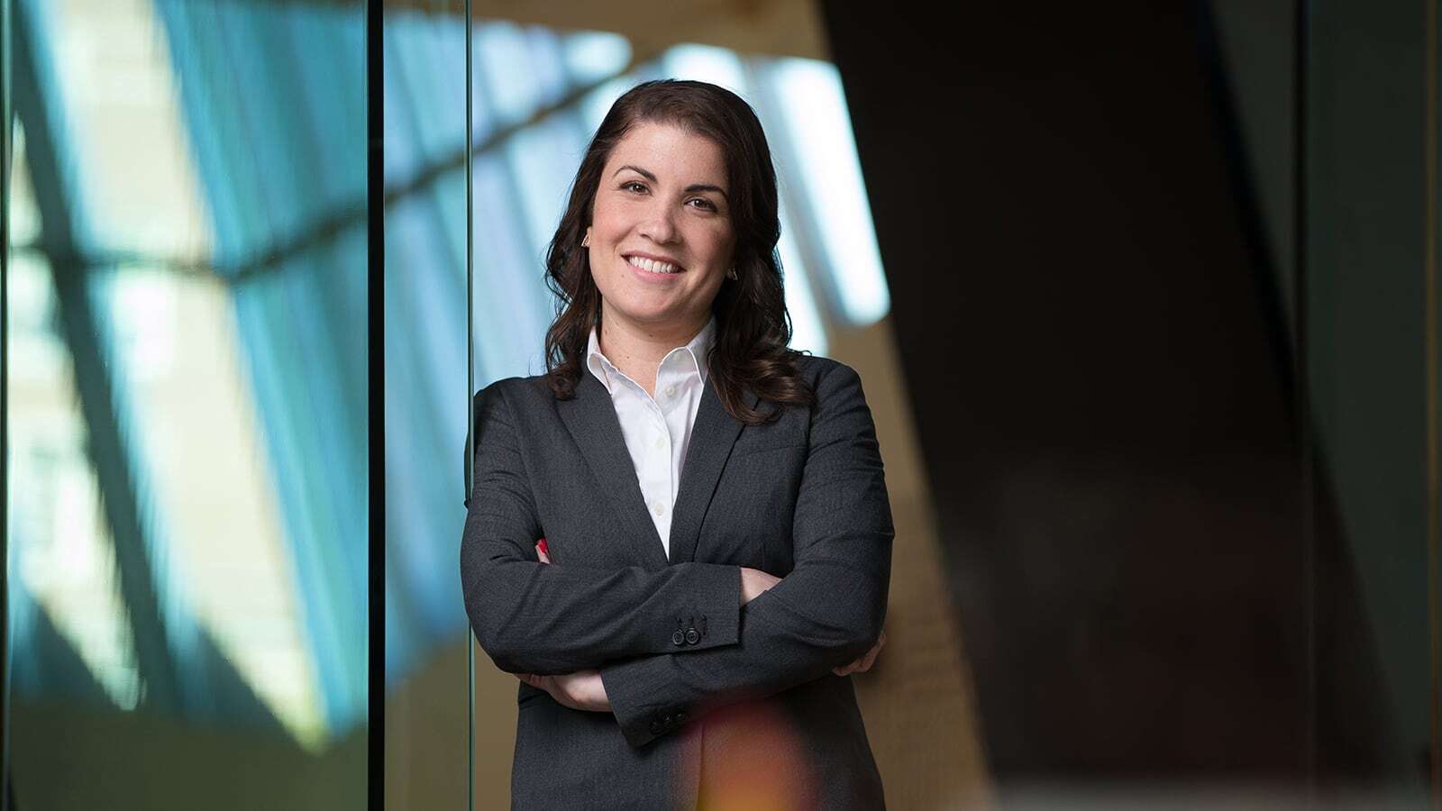 Full-Time MBA student standing in front of glass with arms crossed.