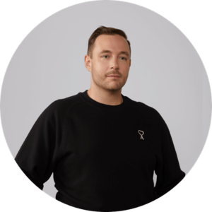 Professional headshot of John Roescher, cofounder and CEO of Handsome, in front of a gray background.