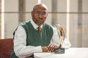Bright image of Matthew Anderson, associate professor of accounting and information systems, seated and his PhD Project award on the table beside him.