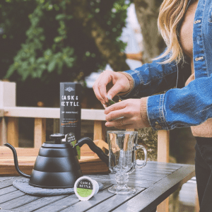 A woman prepares a drink using a Cask & Kettle product.