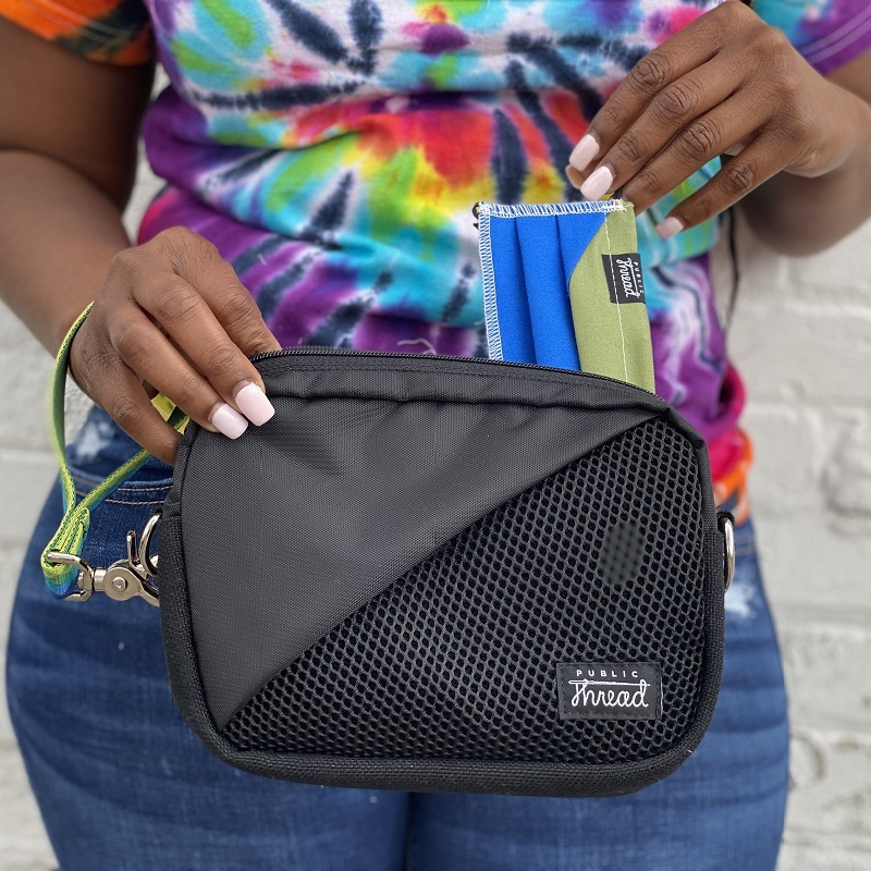 Close-up of woman using Public Thread fanny pack and pulling out a face mask.